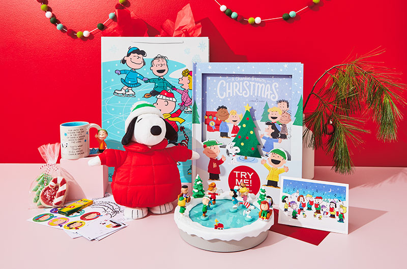 Gifts including a Charlie Brown Christmas pop-up book, blanket featuring the Peanuts gang ice-skating, a musical tabletop figurine of the ice-skating friends, a Snoopy pillow, plush Snoopy in a parka, Linus snow globe and matching Linus mug, featuring his Christmas speech and Snoopy socks