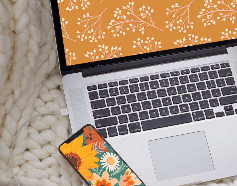 A laptop and smartphone displaying the free November digital wallpapers.