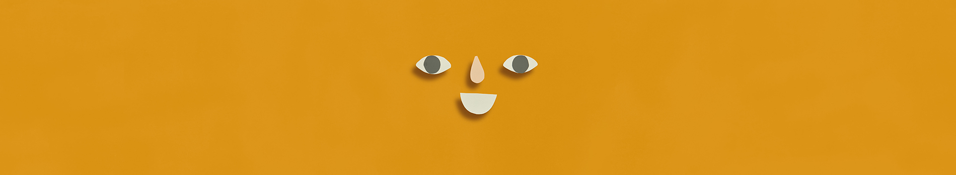Paper cut shapes arranged in a smiling face on a dark yellow background