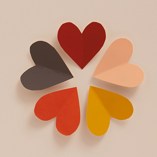 Paper hearts in different colors on a beige background