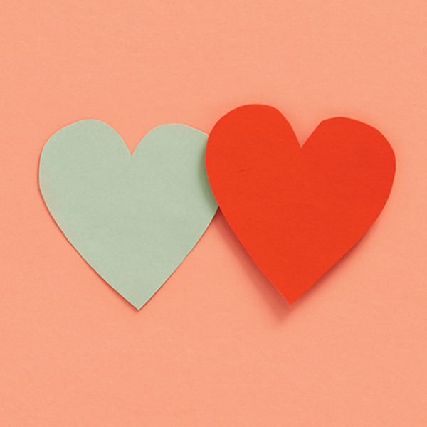 A mint-colored heart and a red heart on a peach colored background