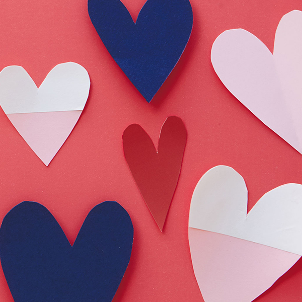 A red background with navy blue, red and pink and white paper heart cutouts scattered across it.