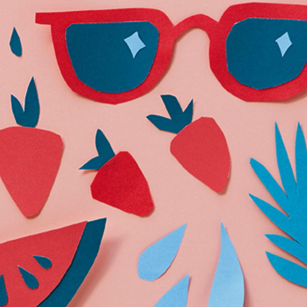 Paper cut sunglasses, berries and melon shapes on a light pink surface