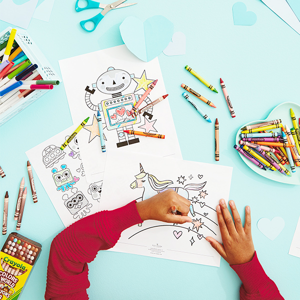 Young boy's hands coloring free Valentine's Day coloring pages with Crayola crayons.