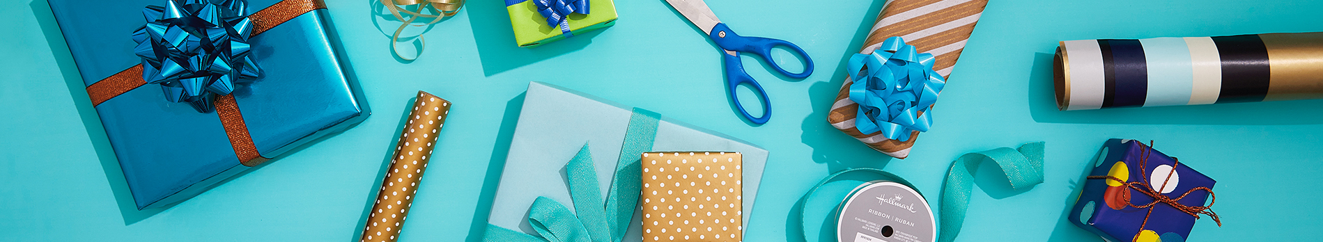 Gift wrapping supplies on a bright aqua background.