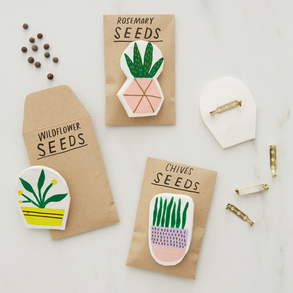 Homemade seed packets with DIY clay plant pins affixed to them.
