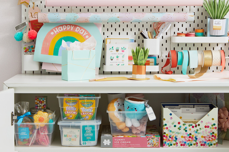 A bright and colorful gift closet setup for kids, with Crayola crayons, Better Together plushes, candy, ribbons and a confetti-patterned card organizer.