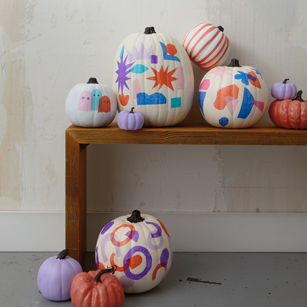A variety of tissue paper decoupage pumpkins arranged on a wooden console table.