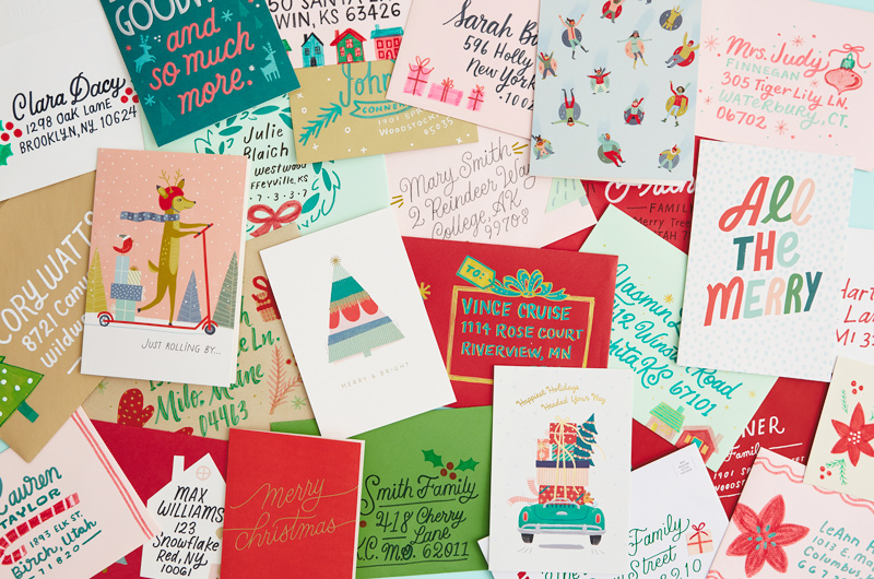 A scattering of holiday cards and decorated envelopes on a tabletop.