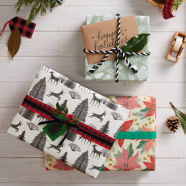 A stack of creatively wrapped Christmas gifts in a variety of wrapping paper patterns and colors.