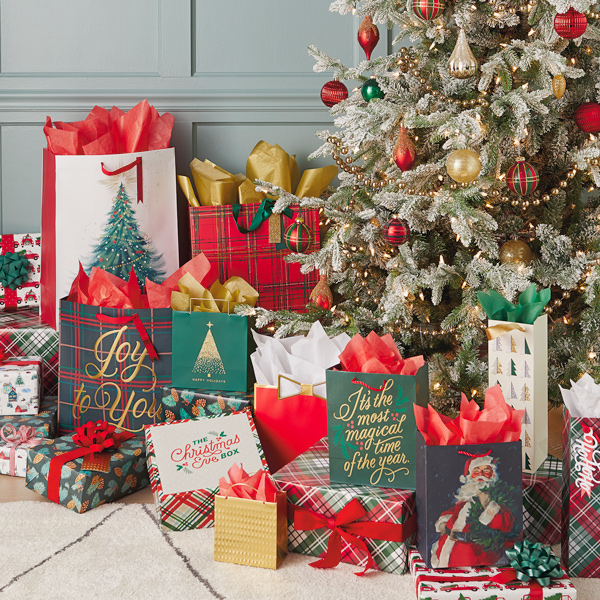A pile of Christmas presents wrapped in gift wrap, bags and tissue in traditional holiday colors of red, green and white.