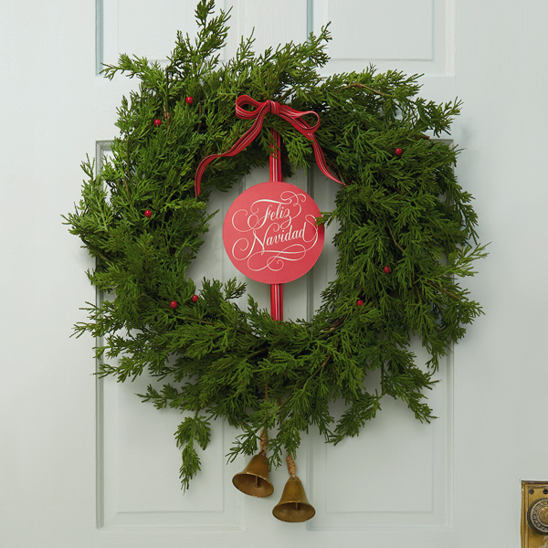 An evergreen wreath with a banner in the center that reads, 