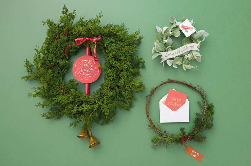 Three holiday wreaths of varying sizes and styles personalized with our free printable banners.