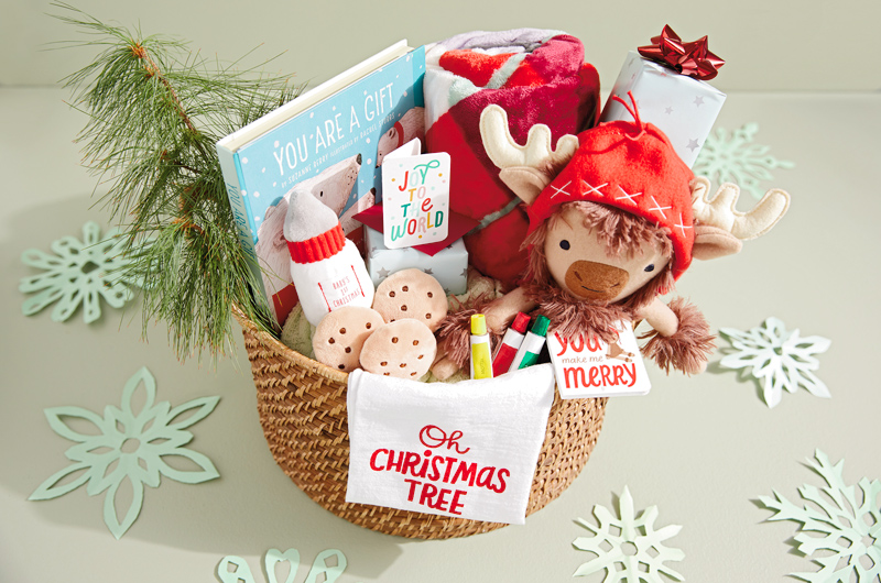 A Christmas care package for a baby or new parents, filled with stuffed animals, a plush blanket, book and more.