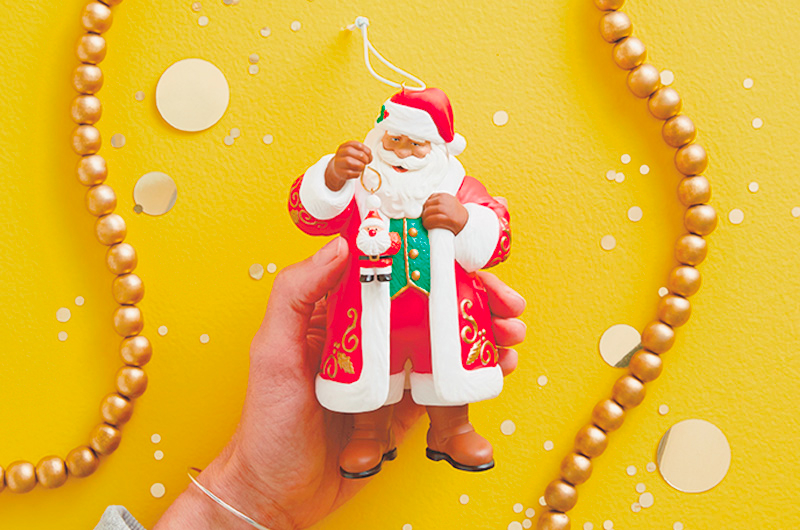 A hand holding a Keepsake Ornament Santa Clause figurine.