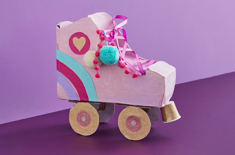 A valentine box shaped like a roller skate, decorated with pom-poms and glittery wheels.