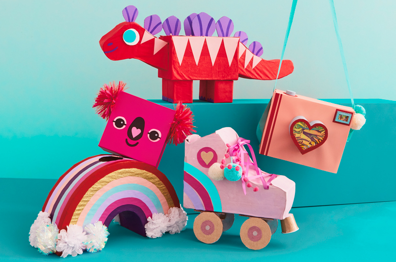 A group of valentine boxes in the shape of fun objects, including a camera, a roller skate, a rainbow, a koala and a dinosaur.