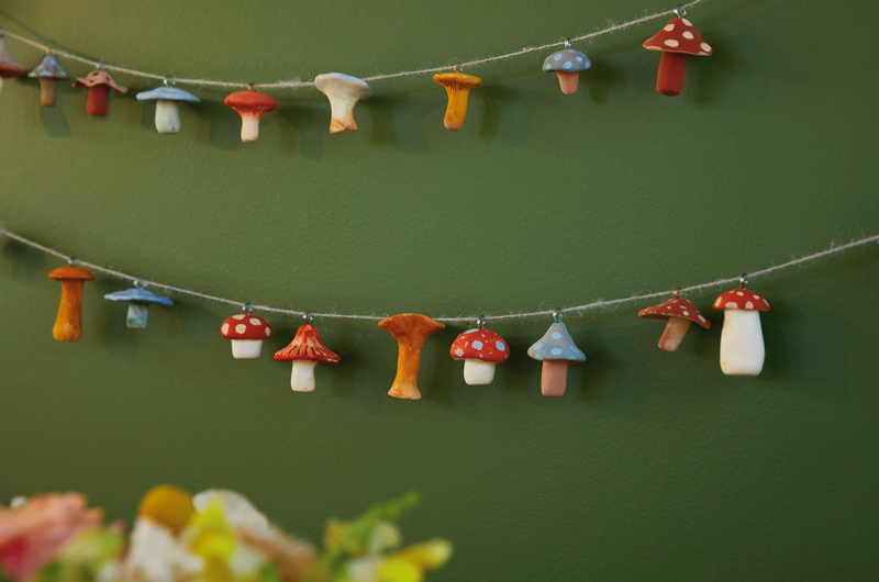 A completed DIY mushroom garland, made with air-dry clay that's been molded and painted to look like mushrooms, some jump rings, and twine.