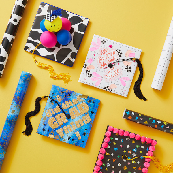 A variety of DIY graduation cap decoration ideas that use Hallmark wrapping paper, cards, balloons, pom poms, cut out sparkly letters, and more.