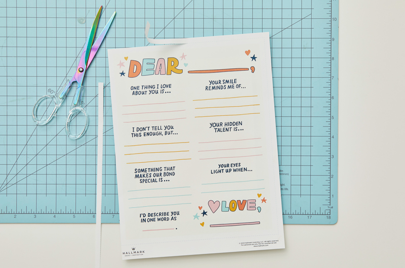 Our free printable writing prompts page lies on a craft mat with a pair of scissors.