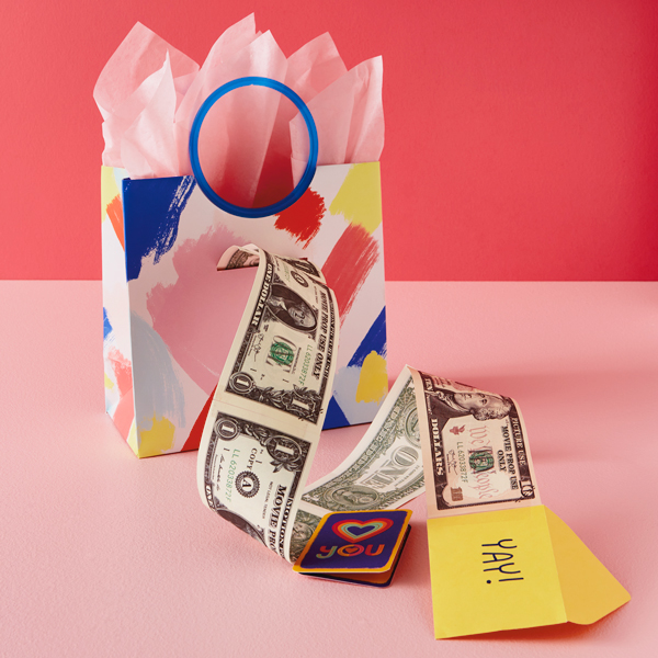 A gift bag with a slit cut in the side to conceal a money-pull gift feature, where the recipient pulls out a mini card attached to a s