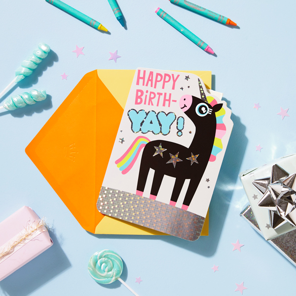 A kid's birthday card with a cartoon unicorn on the front; above the unicorn reads, 