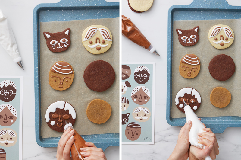 A woman's hands hold a piping bag as she demonstrates how to decorate a baking tray full of cookies to look like different people's and pet's faces; on the left, she shows how to pipe icing to make eyes, and on the right she shows how to use a different color of icing to add details like pupils to the eyes.