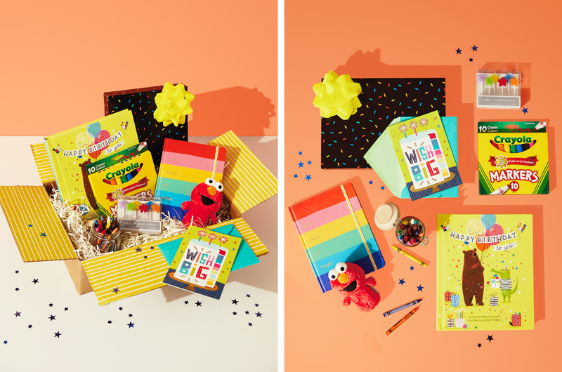 A colorful birthday care package for a kid that includes an Elmo itty bittys plush, a Crayola notebook in rainbow colors, a 10-pack of Crayola markers, a package of colorful, star-shaped birthday candles, a Video Greetings card that says 
