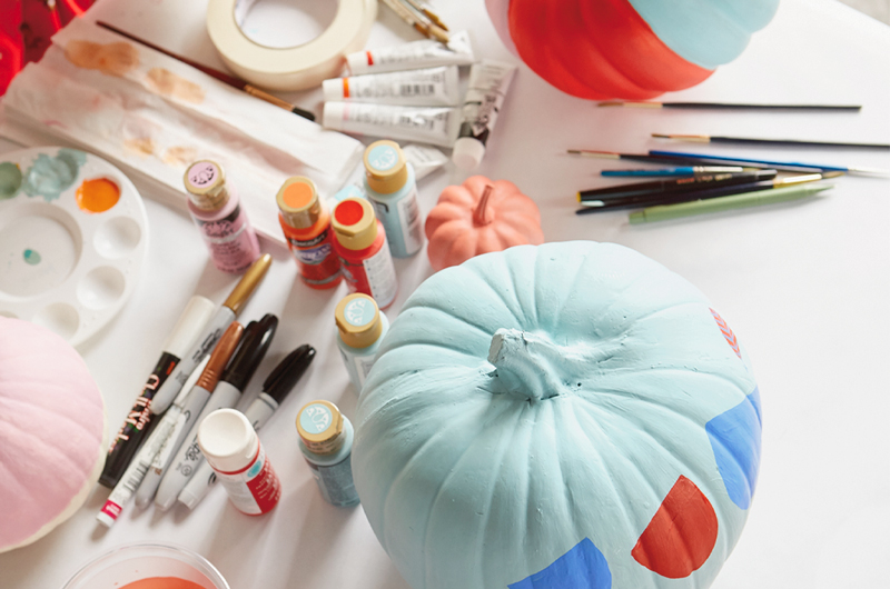 A light blue pumpkin sits next to various art supplies.