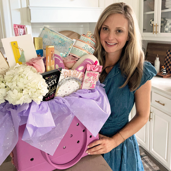 A woman stands next to a large gift bag filled with cards, chocolate bars and small gifts.