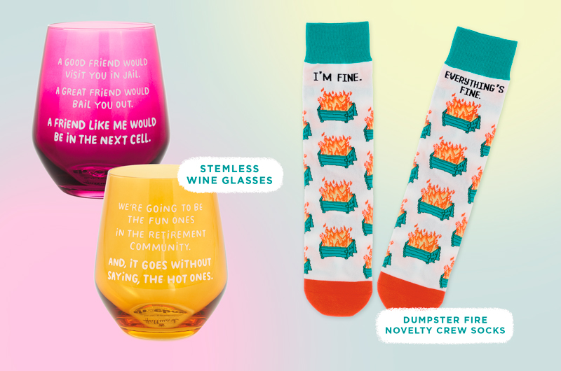 A pair of colorful stemless wine glasses with humorous quotes on them, alongside a pair of novelty socks printed with a repeating pattern of a dumpster on fire and the words, 