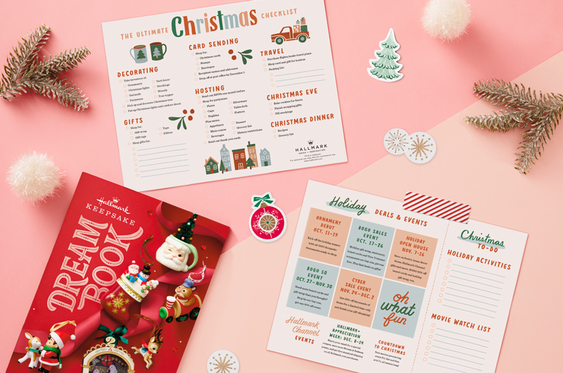 Our free printable Christmas checklist sits on a pastel pink tabletop with sprigs of artificial pine, white pompoms and adhesive gift tags.