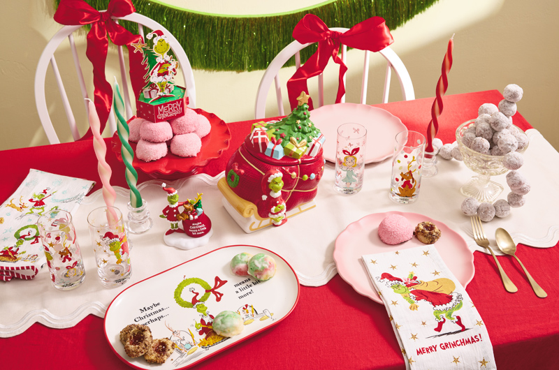 A collection of gifts and decor items featuring Dr. Seuss's The Grinch decorates a tabletop that's been decorated in a whimsical style for the holiday season.