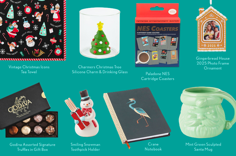 A collection of stocking stuffer gift ideas for men, including a notebook with a crane illustration on the cover, beverage coasters shaped like Nintendo NES game cartridges, a green sculpted Santa mug, a box of chocolate truffles, a photo frame ornament, and a toothpick holder shaped like a snowman.