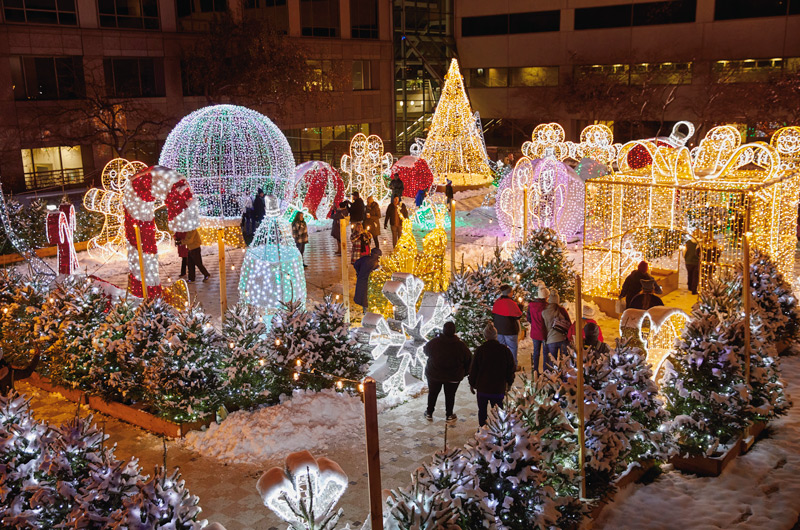 Attendees of the 2024 Hallmark Christmas Experience walk the path of the Light Walk, which is lined with trees, sculptures and figures covered in shining, twinkling Christmas lights.