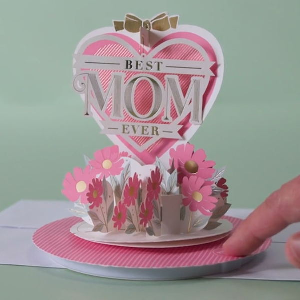 A pop-up Paper Wonder Mother's Day card with music and motion sits on a mint-green sweep; the card features a heart with cut-paper details that read 