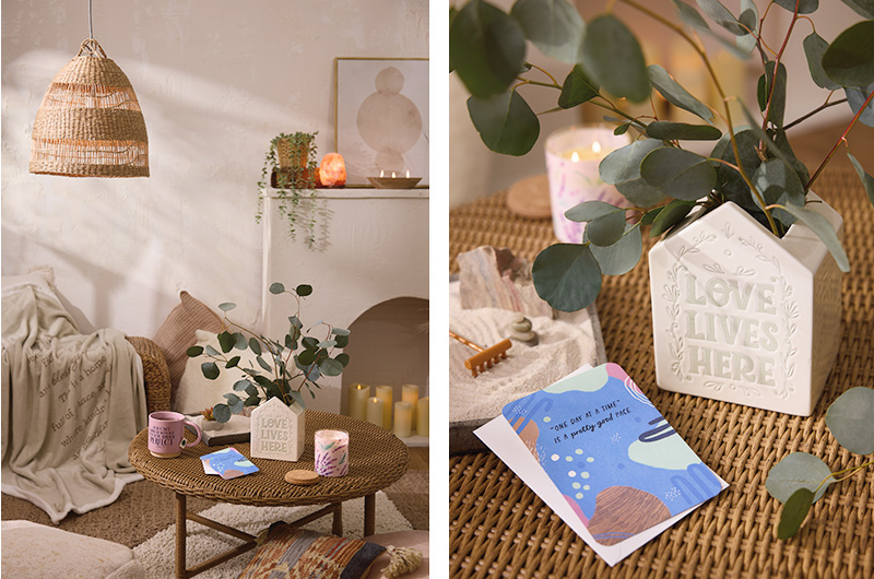 A vignette setting showing what a spa-like calming corner for adults could look like, with wicker furniture, live plants, soothing neutral colors, candles, soft blankets and comforting items like an aroma therapy candle, a mug of tea and a mini zen garden.