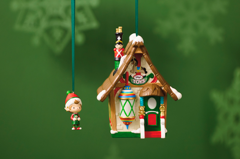 The second in the Welcome to Elfville Keepsake Ornament series, a small elf ornament and a larger ornament shaped like the elf's toy store with a sign on the front that says 
