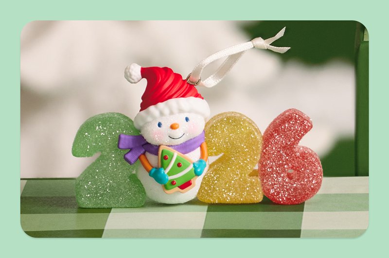 A Keepsake Ornament from the Sweet Decade series; this 2026 ornament features numerals that look like sugar-coated gummy candy, and a little snowman holding an iced sugar cookie shaped like a Christmas tree.