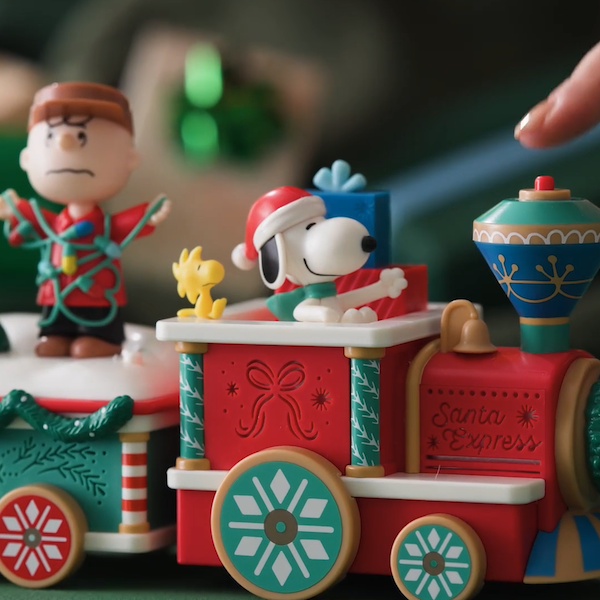 A tabletop figurine with sound and motion in the shape of a holiday train conveying members of the Peanuts Gang.