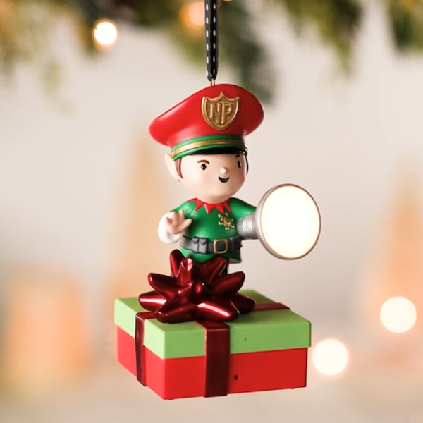 A Keepsake Ornament portrays a North Pole elf holding a flashlight and sitting atop a wrapped gift; when the ornament detects motion, it reacts with various messages about not peeking at gifts until Christmas.