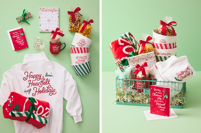 Hallmark Channel-themed holiday gift basket filled with cozy movie-night items, including a white sweatshirt, blanket, mugs, popcorn tubs, snacks, holiday popcorn, and Hallmark Channel-themed accessories on a mint green background.