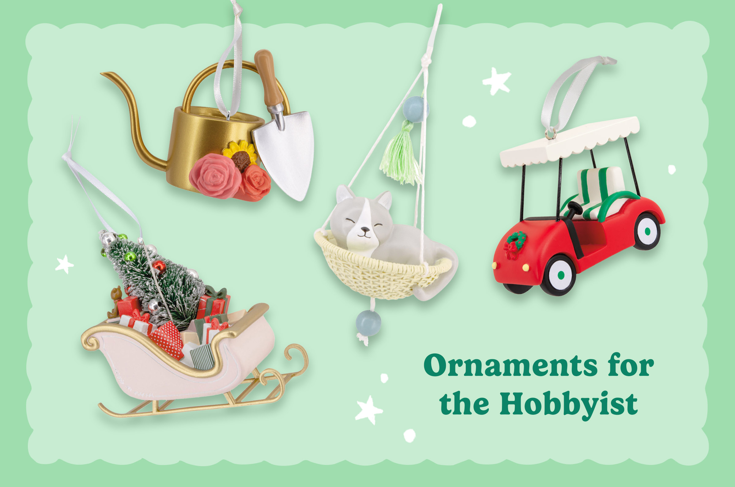 Collection of hobby-inspired Christmas ornaments including a flower-adorned watering can and garden trowel, a sleeping cat in a hanging basket, a festive golf cart, and a sleigh filled with gifts and a Christmas tree on a mint-green background with the heading “Ornaments for the Hobbyist.”