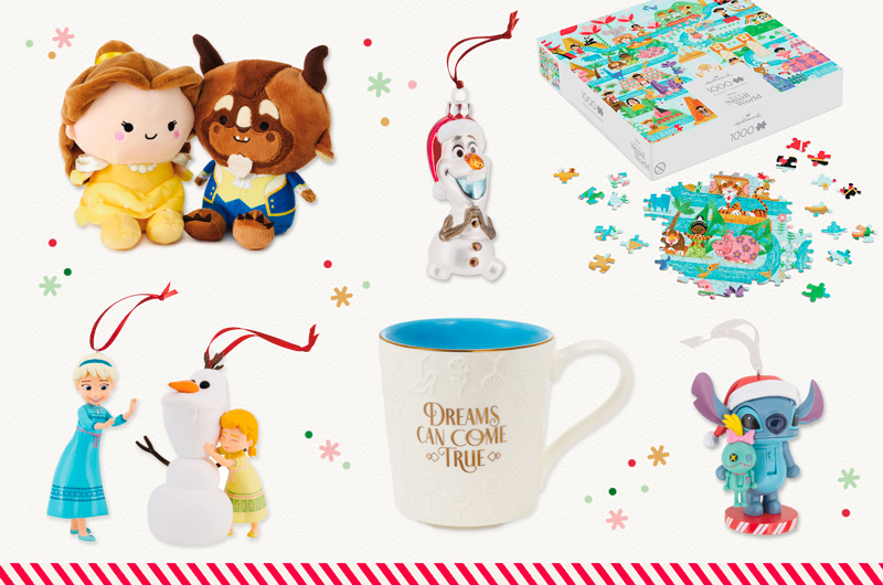 A collection of Disney-themed gifts featuring beloved Disney characters; gifts include a pair of magnetic plushies shaped like Beauty and the Beast; a pair of ornaments in the form of a little girl version of both Elsa and Anna from Disney Frozen, playing with a snowman that can be recognized as Olaf; a ceramic mug with gold metallic accents and an embossed floral treatment on the outside that reads, 