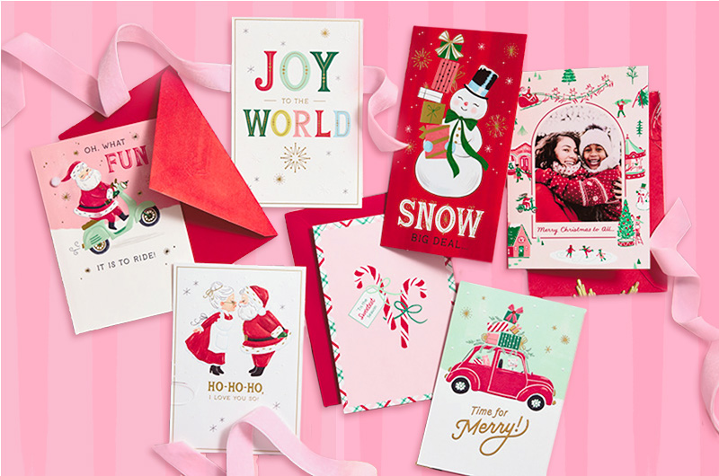 A collection of vintage-inspired Christmas cards lie on a pink striped surface