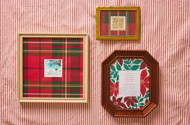 Pieces of memorabilia have been placed in decorative frames with Christmas gift wrap serving as the matting; items inside the frames include ticket stubs, an instant photo, and the inside of a Christmas card with the sender's handwritten message.